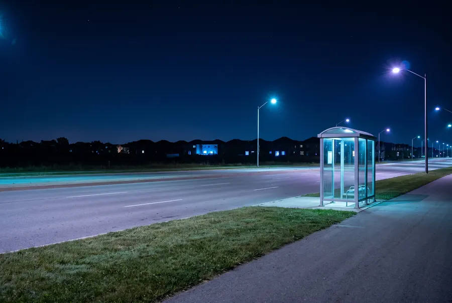 Lone glass bus shelter by an empty road